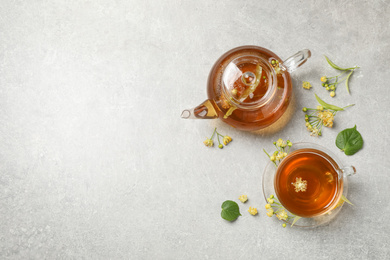 Photo of Tasty tea and linden blossom on light grey table, flat lay. Space for text