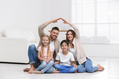 Photo of Happy family forming house roof with their hands at home. Insurance concept