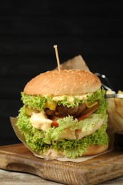 Photo of Burger with delicious patty on wooden table against dark background