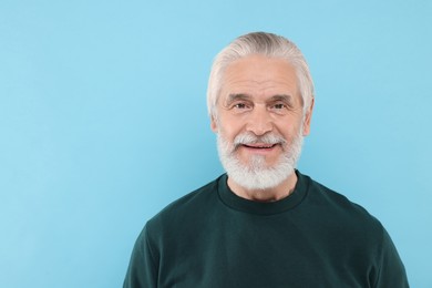 Portrait of handsome senior man on light blue background. Space for text