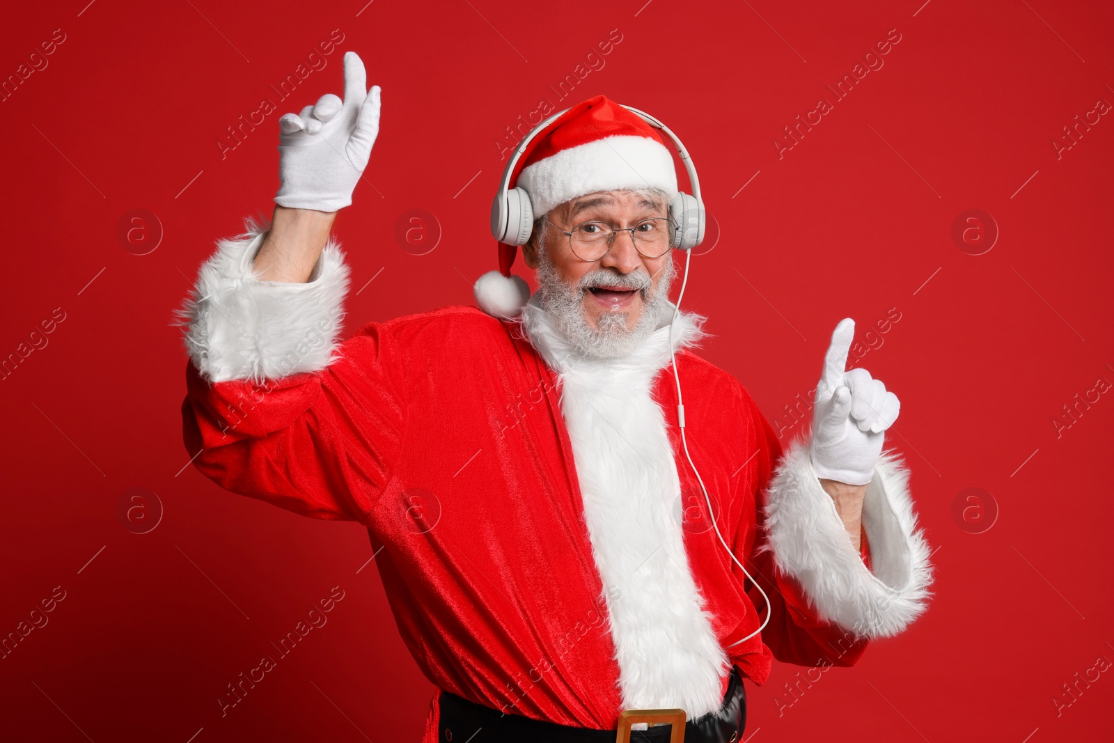 Photo of Merry Christmas. Santa Claus in headphones listening to music on red background