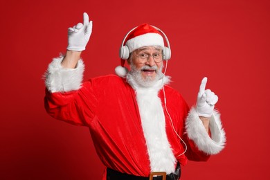 Photo of Merry Christmas. Santa Claus in headphones listening to music on red background