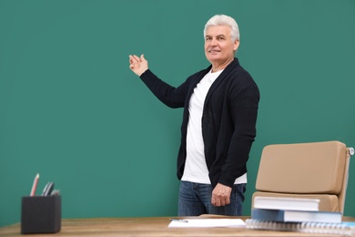 Portrait of senior teacher at green chalkboard and table