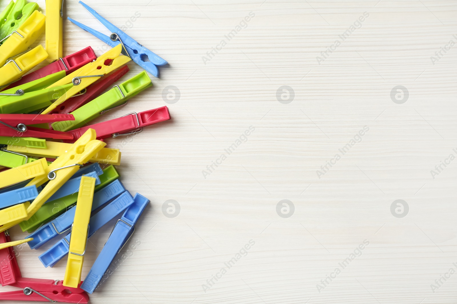 Photo of Colorful plastic clothespins on white wooden table, flat lay. Space for text