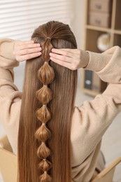 Woman with braided hair indoors, back view