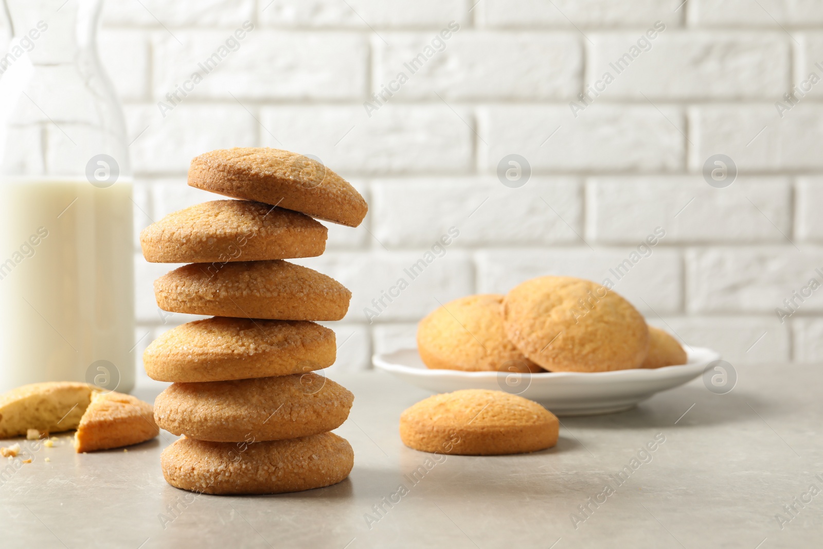 Photo of Stack of Danish butter cookies and milk on table against brick wall. Space for text