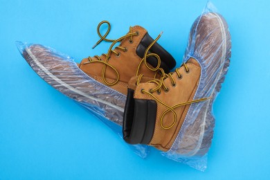 Men's boots in shoe covers on light blue background, top view