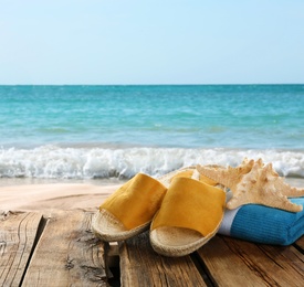 Image of Beach accessories on wooden surface near ocean, space for text