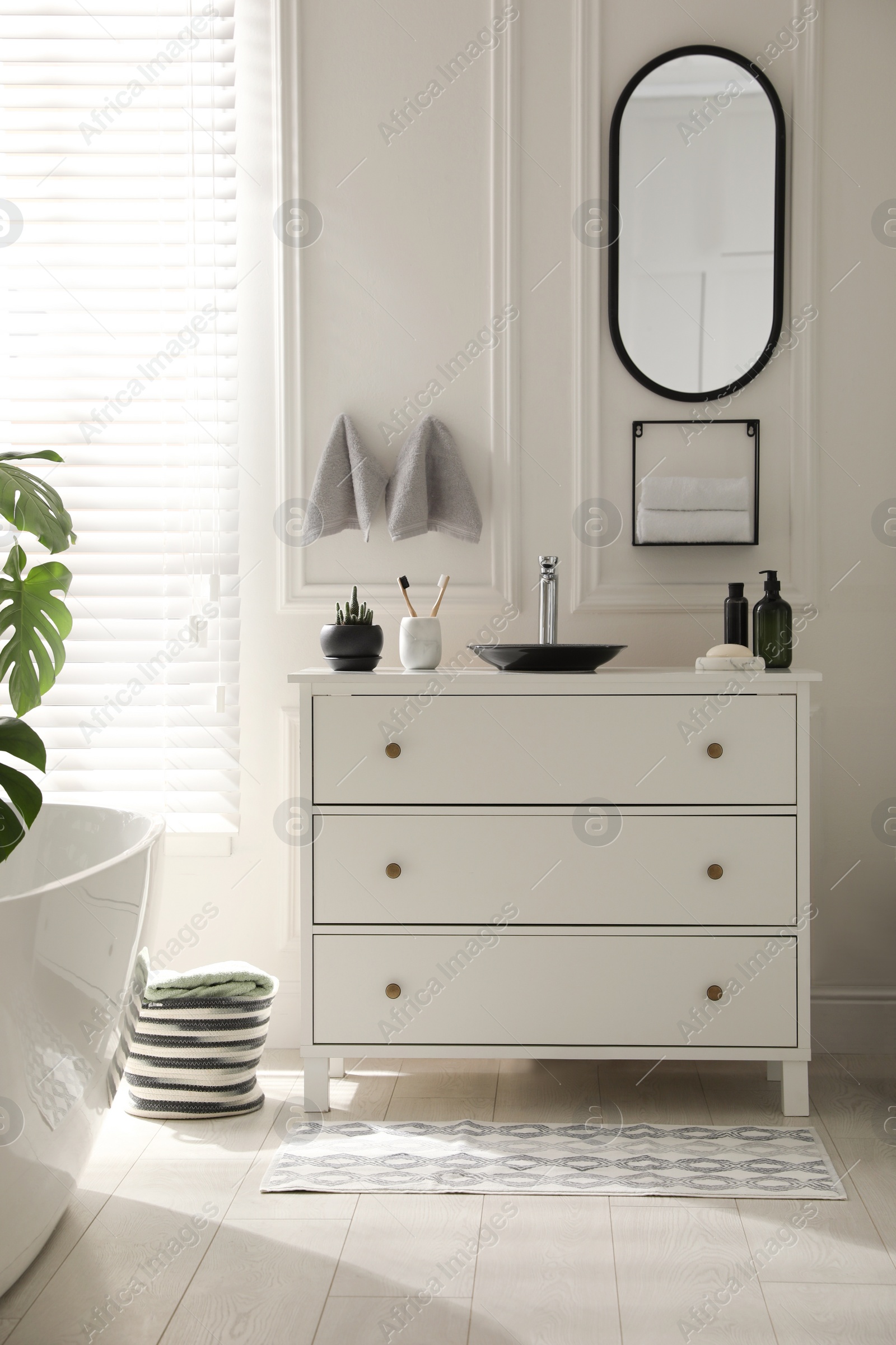 Photo of Stylish mat with pattern near chest of drawers in bathroom