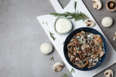 Bowl of mushrooms with sauce on grey background, flat lay. Space for text