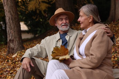 Photo of Affectionate senior couple with dry leaves in autumn park