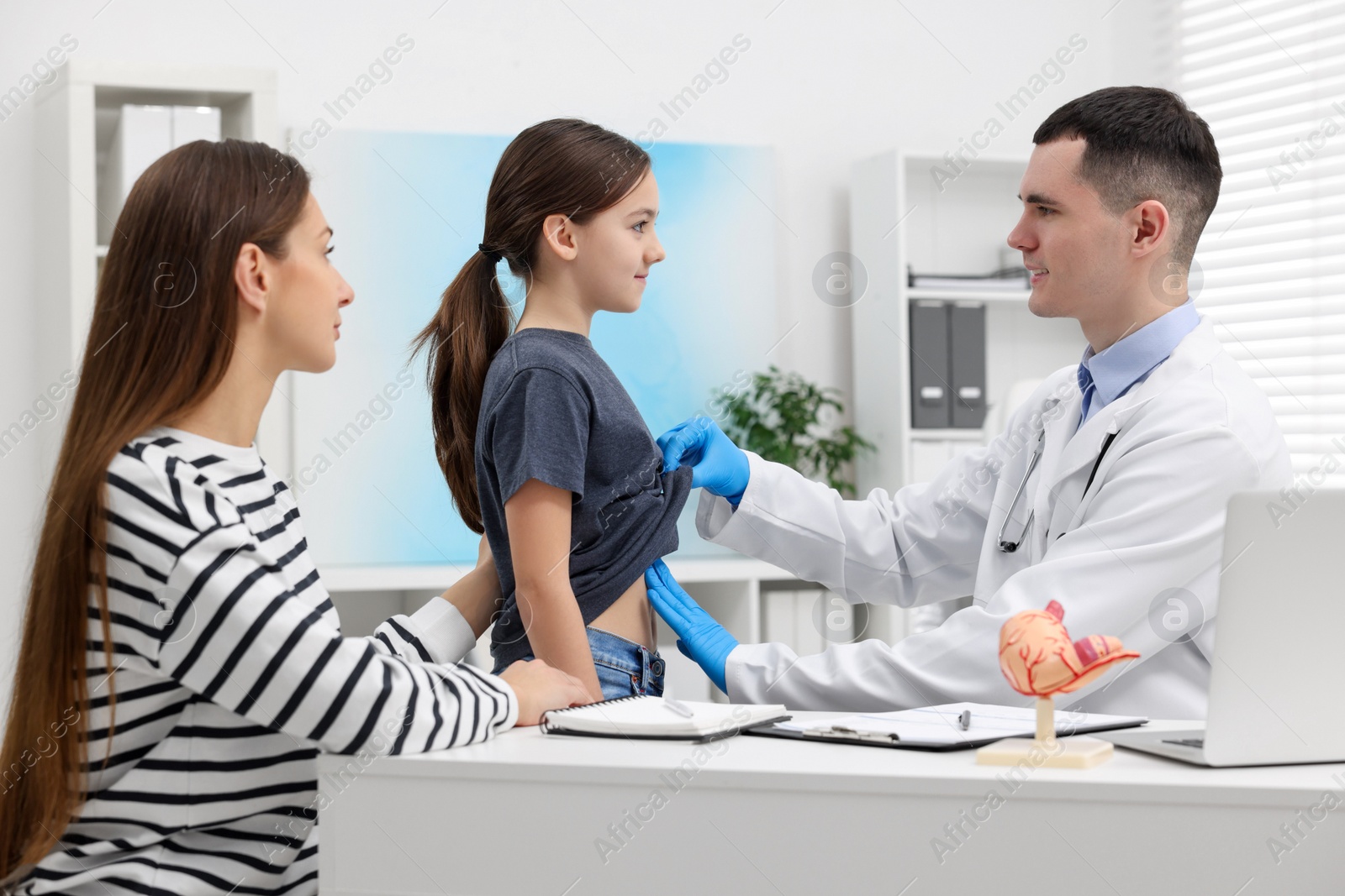 Photo of Gastroenterologist examining girl with stomach ache in clinic