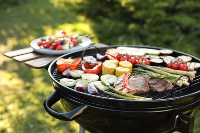Delicious grilled vegetables and meat on barbecue grill outdoors, closeup