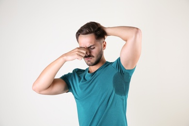 Photo of Sweaty man with stain on t-shirt against white background. Using deodorant