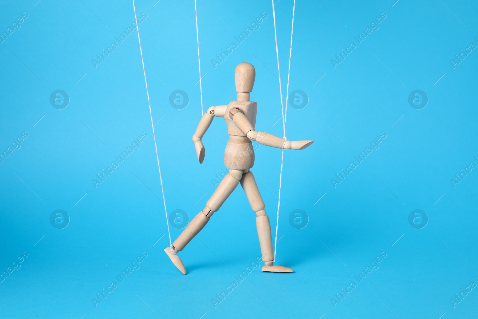 Photo of One wooden puppet with strings on light blue background