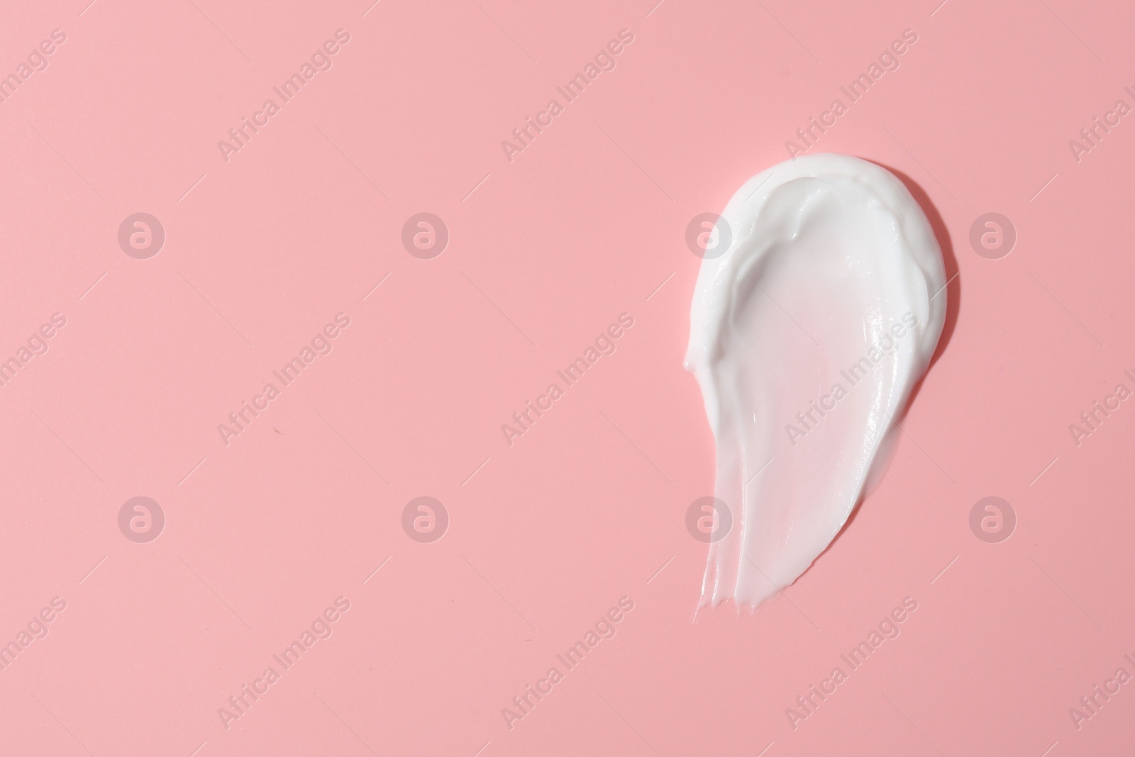 Photo of Sample of face cream on pink background, top view. Space for text