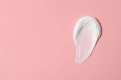 Photo of Sample of face cream on pink background, top view. Space for text