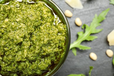 Photo of Bowl of tasty arugula pesto on black table, closeup. Space for text