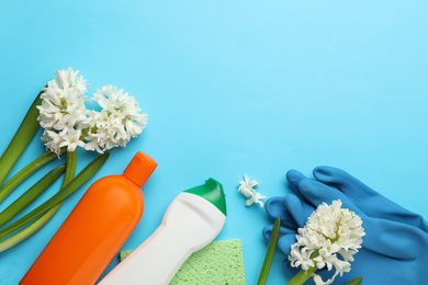 Photo of Composition with spring flowers and cleaning supplies on light blue background, flat lay. Space for text