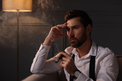 Tired man smoking cigar at home in evening