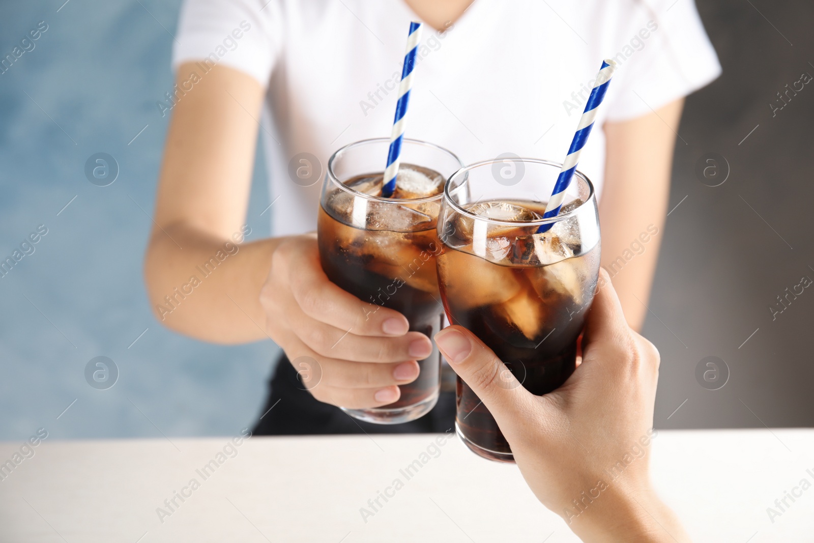 Photo of Friends with glasses of tasty refreshing cola at table, closeup view