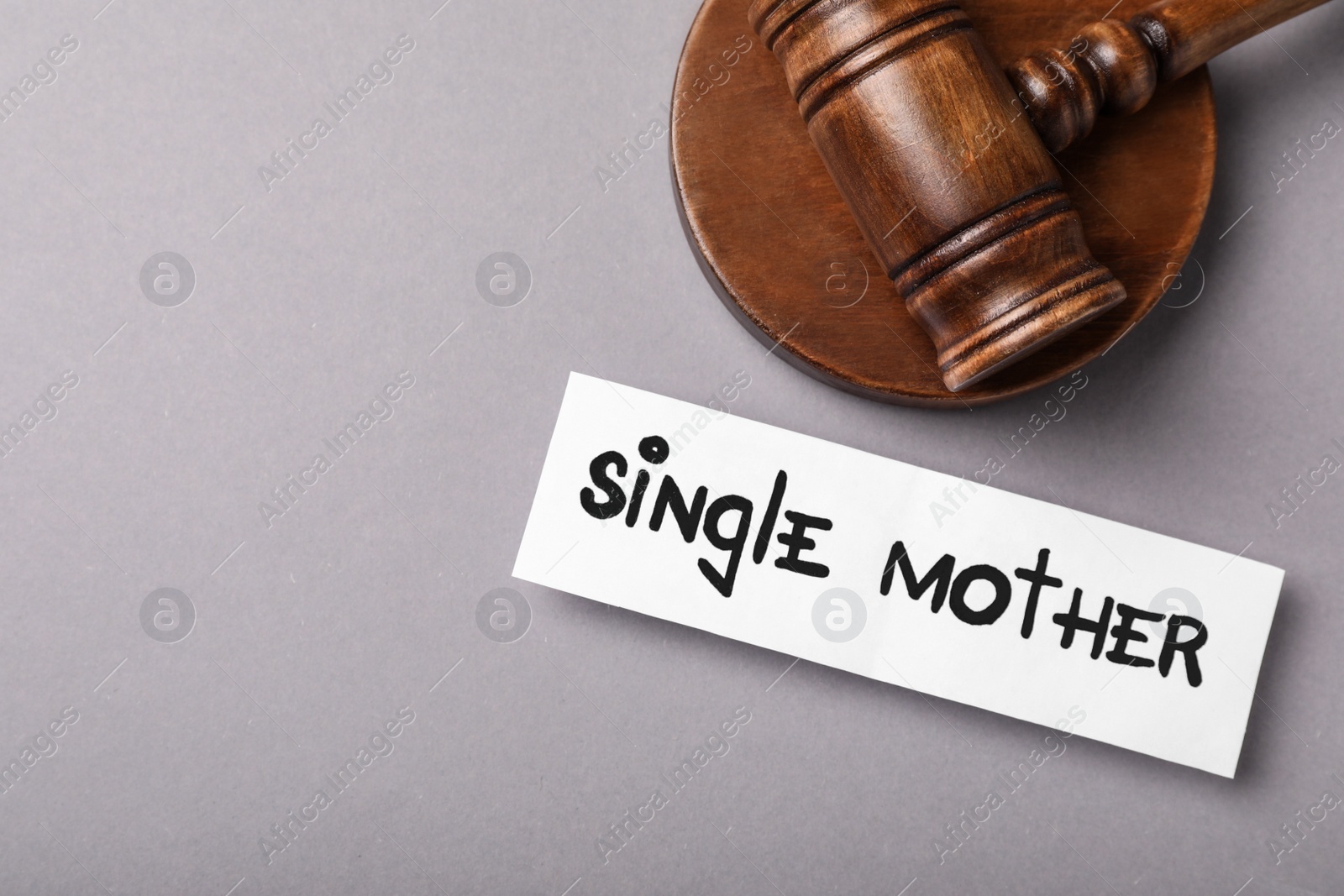 Photo of Being single mother after divorce concept. Card and judge gavel on grey background, flat lay