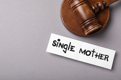 Being single mother after divorce concept. Card and judge gavel on grey background, flat lay