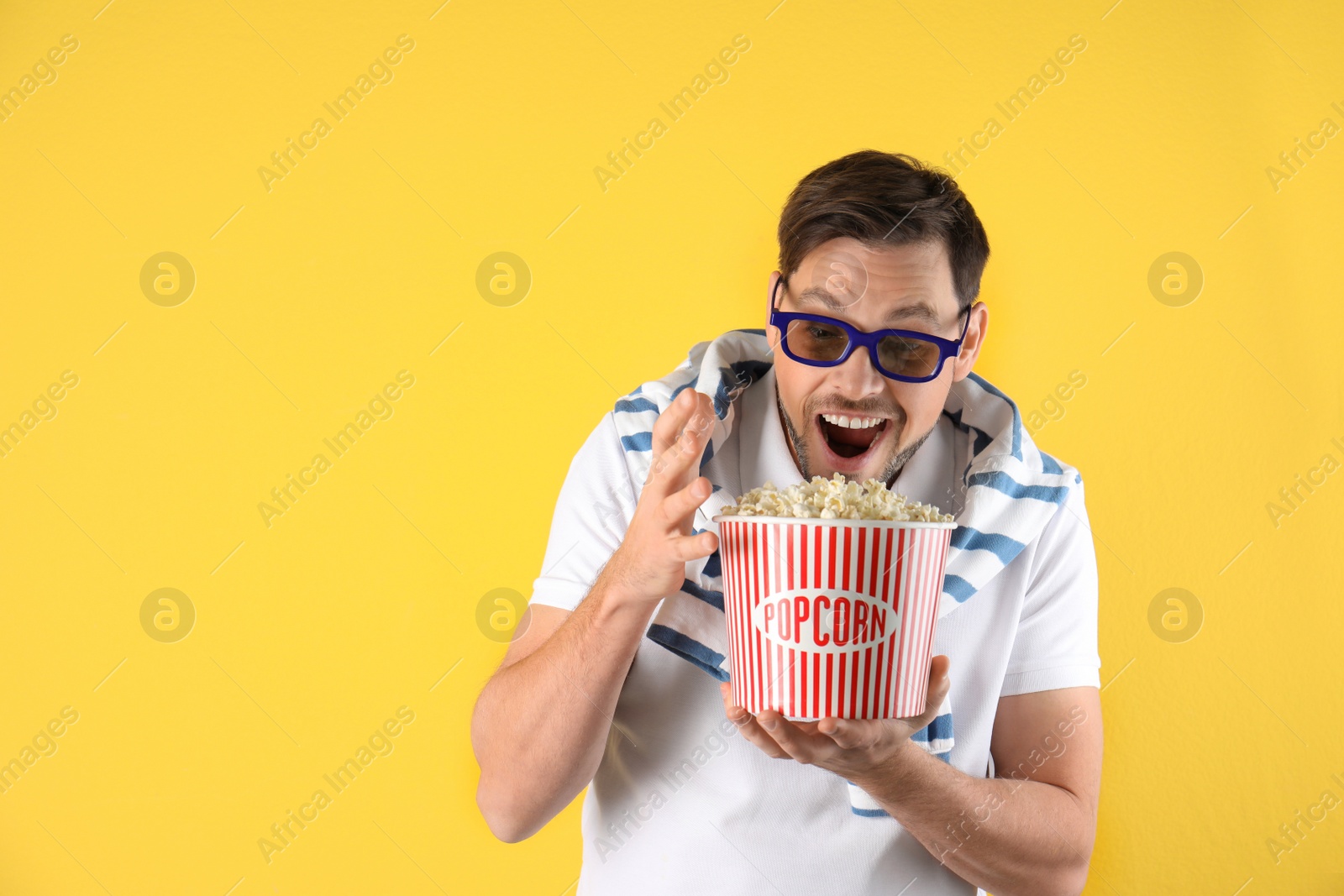 Photo of Emotional man with 3D glasses and tasty popcorn on color background. Space for text