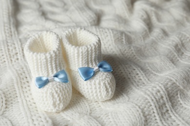 Handmade baby booties on soft plaid. Space for text