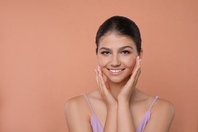 Photo of Portrait of pretty girl on pale coral background, space for text. Beautiful face with perfect smooth skin