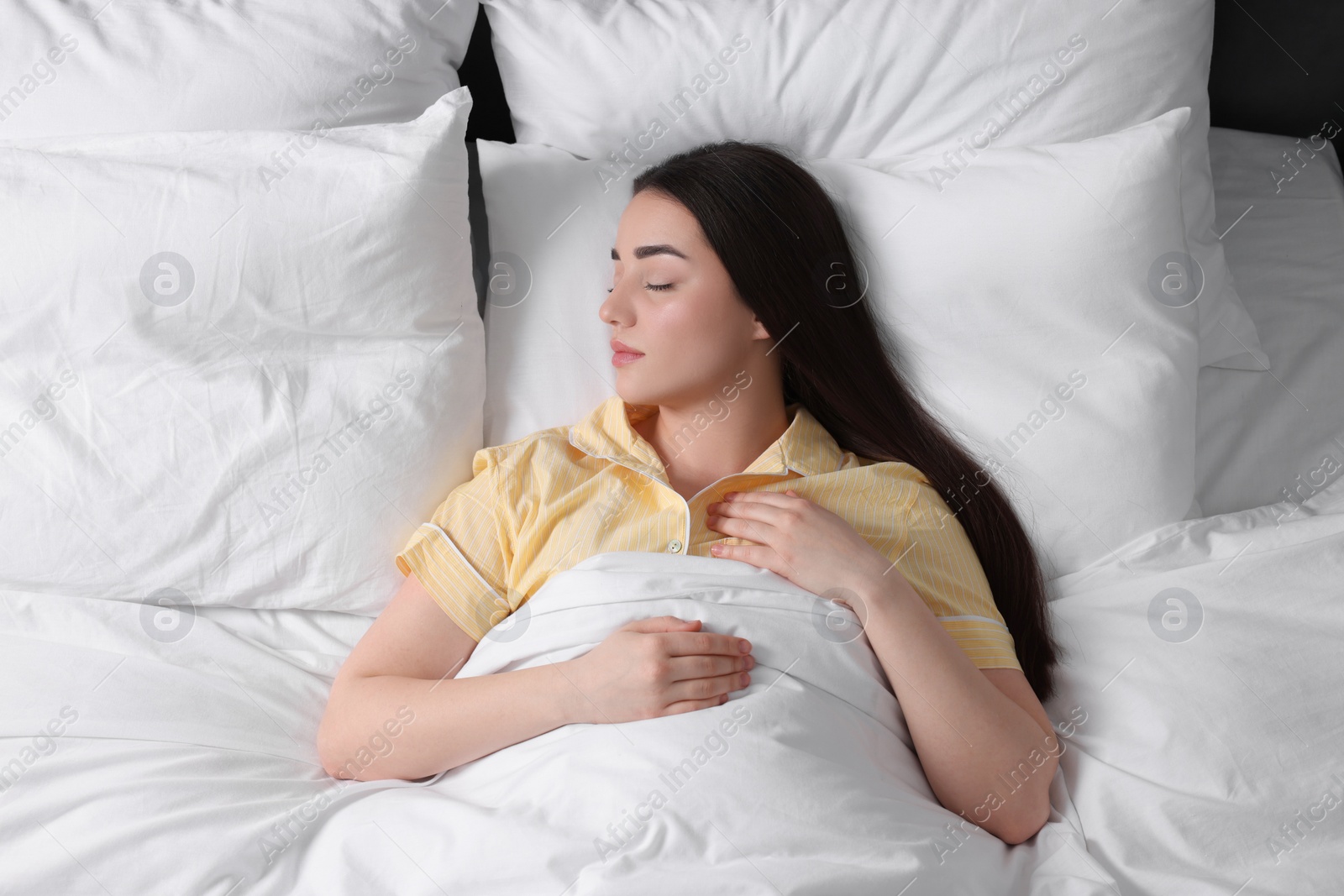 Photo of Beautiful young woman sleeping in soft bed, above view