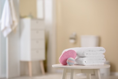 Photo of Clean towels and toiletries on table against blurred background