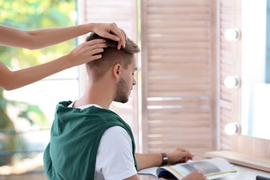 Photo of Professional hairdresser working with young man in barbershop. Trendy hair color