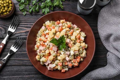 Photo of Delicious salad Olivier on black wooden table, flat lay