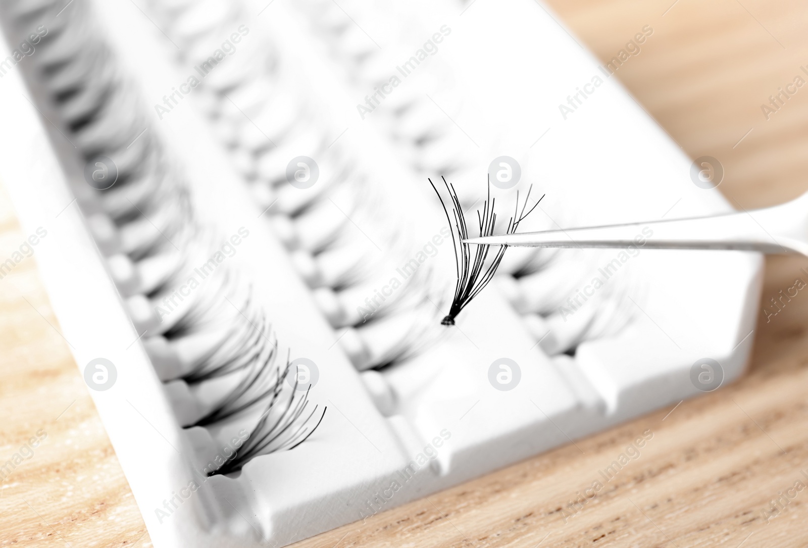 Photo of Woman holding tweezers with false eyelash, closeup