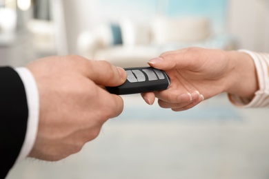 Photo of Man and woman holding car smart key indoors, closeup