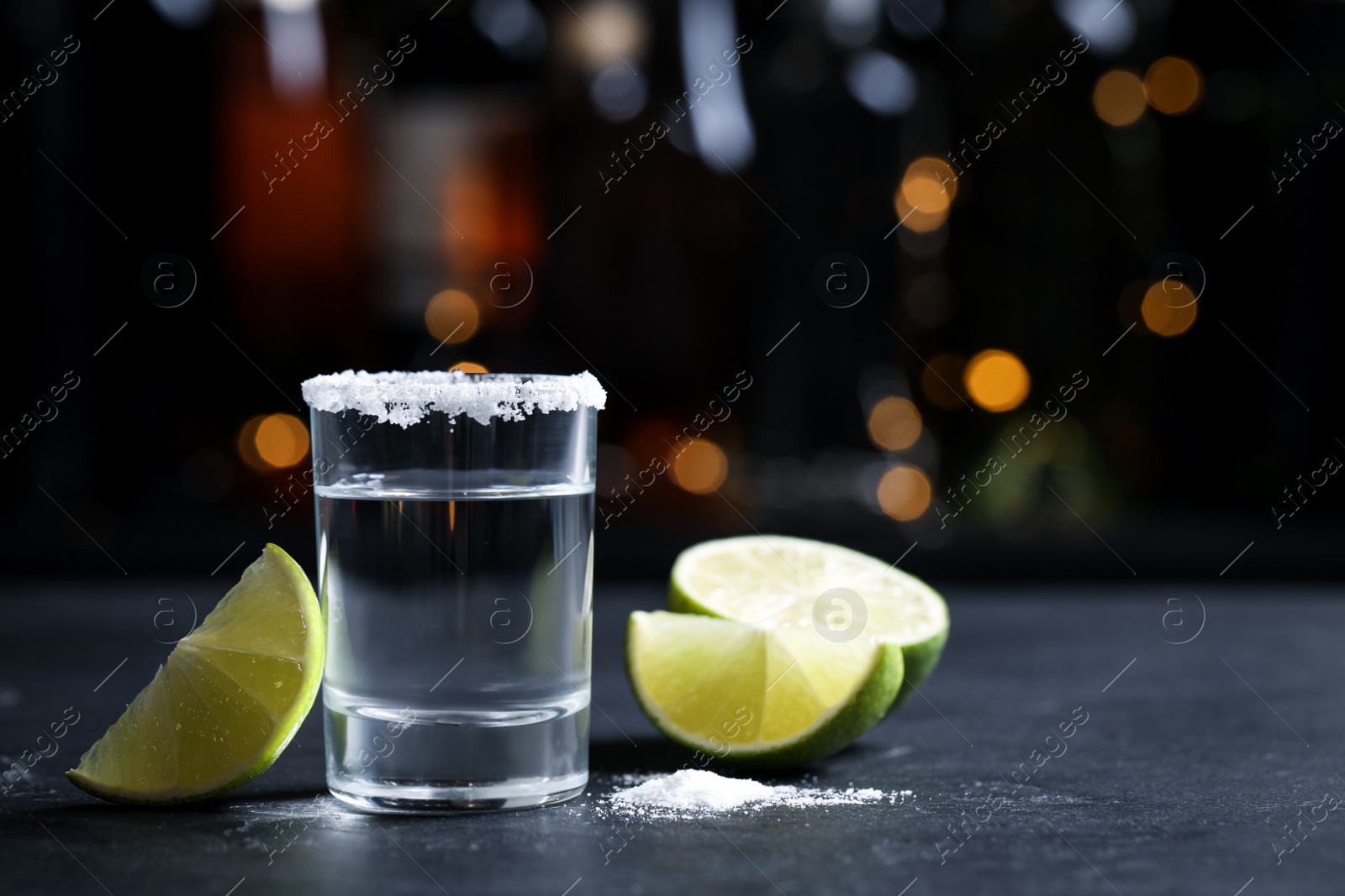 Photo of Mexican Tequila shot with lime slices and salt on bar counter. Space for text