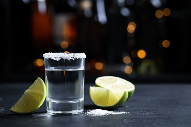 Photo of Mexican Tequila shot with lime slices and salt on bar counter. Space for text