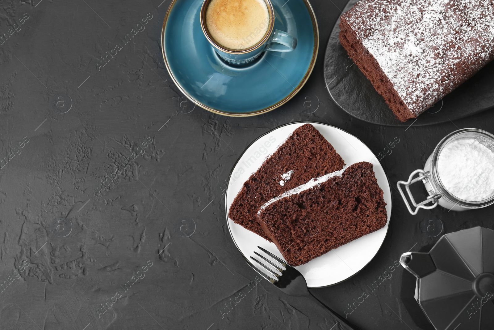 Photo of Tasty chocolate sponge cake with powdered sugar and coffee on black textured table, flat lay. Space for text