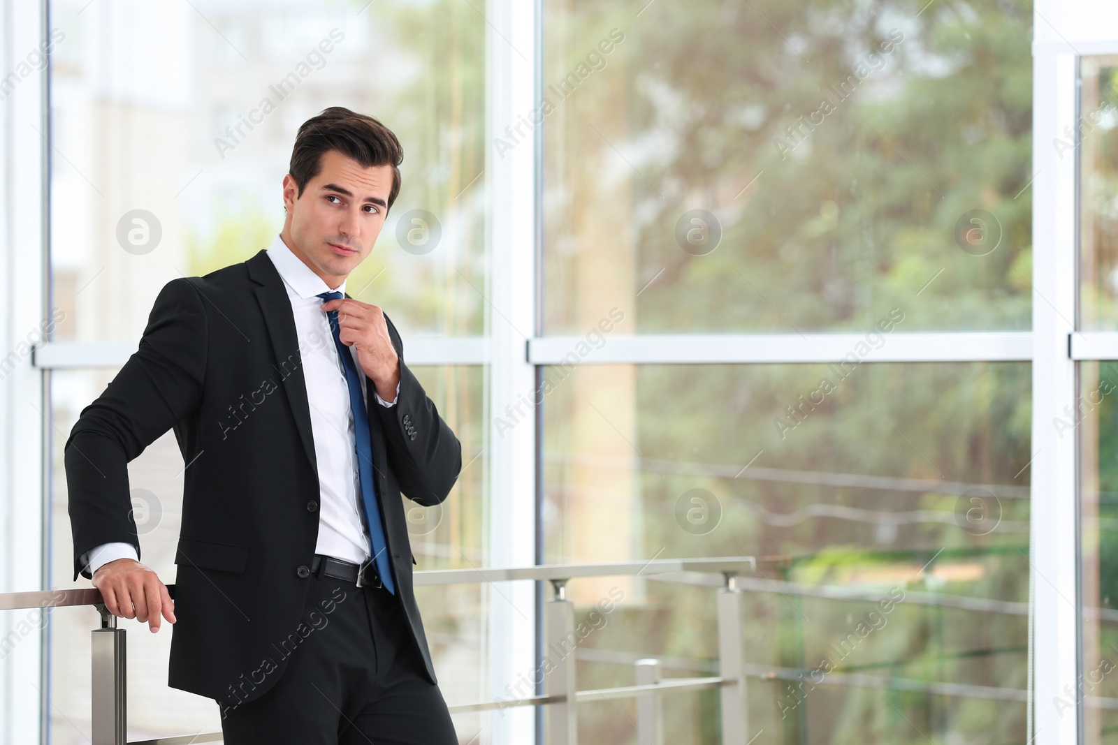 Photo of Handsome young man in stylish suit indoors. Space for text