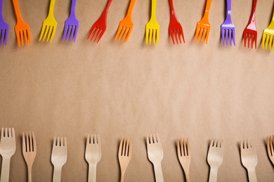 Photo of Flat lay composition with plastic and wooden forks on beige background, space for text. Recycling concept