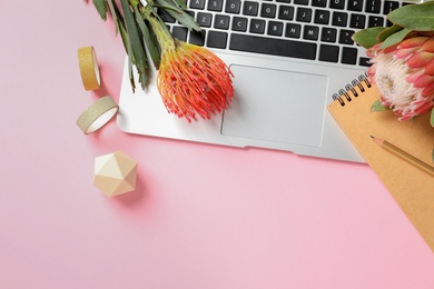 Creative flat lay composition with tropical flowers and laptop on color background