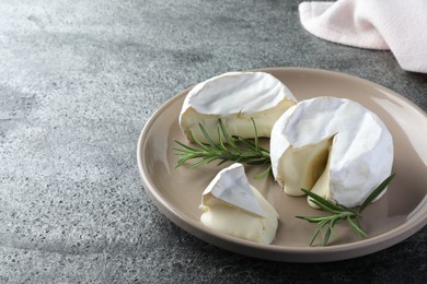 Photo of Delicious brie cheese with rosemary on grey table. Space for text
