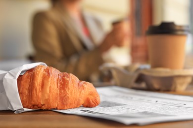 Photo of Woman with coffee in outdoor cafe, focus on croissant