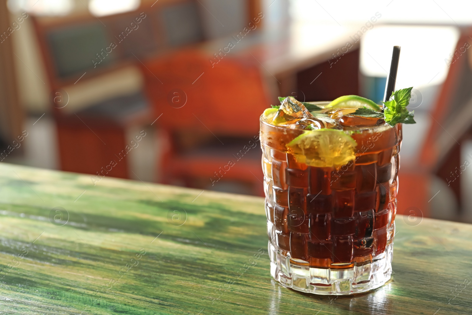 Photo of Glass of delicious cocktail with ice on table in bar