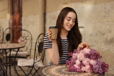 Photo of Beautiful woman with bouquet of spring flowers and coffee in outdoor cafe, space for text