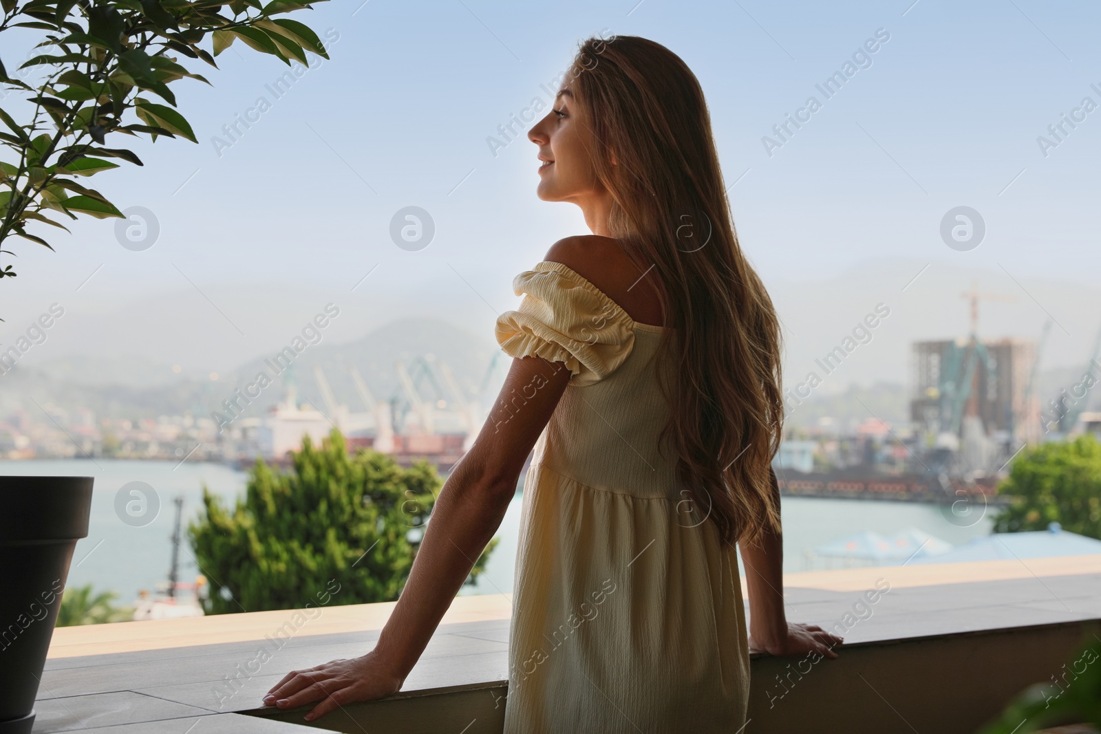 Photo of Beautiful young woman with long hair standing on balcony