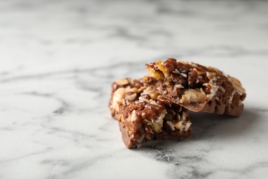 Photo of Pieces of tasty protein bar on marble table. Space for text