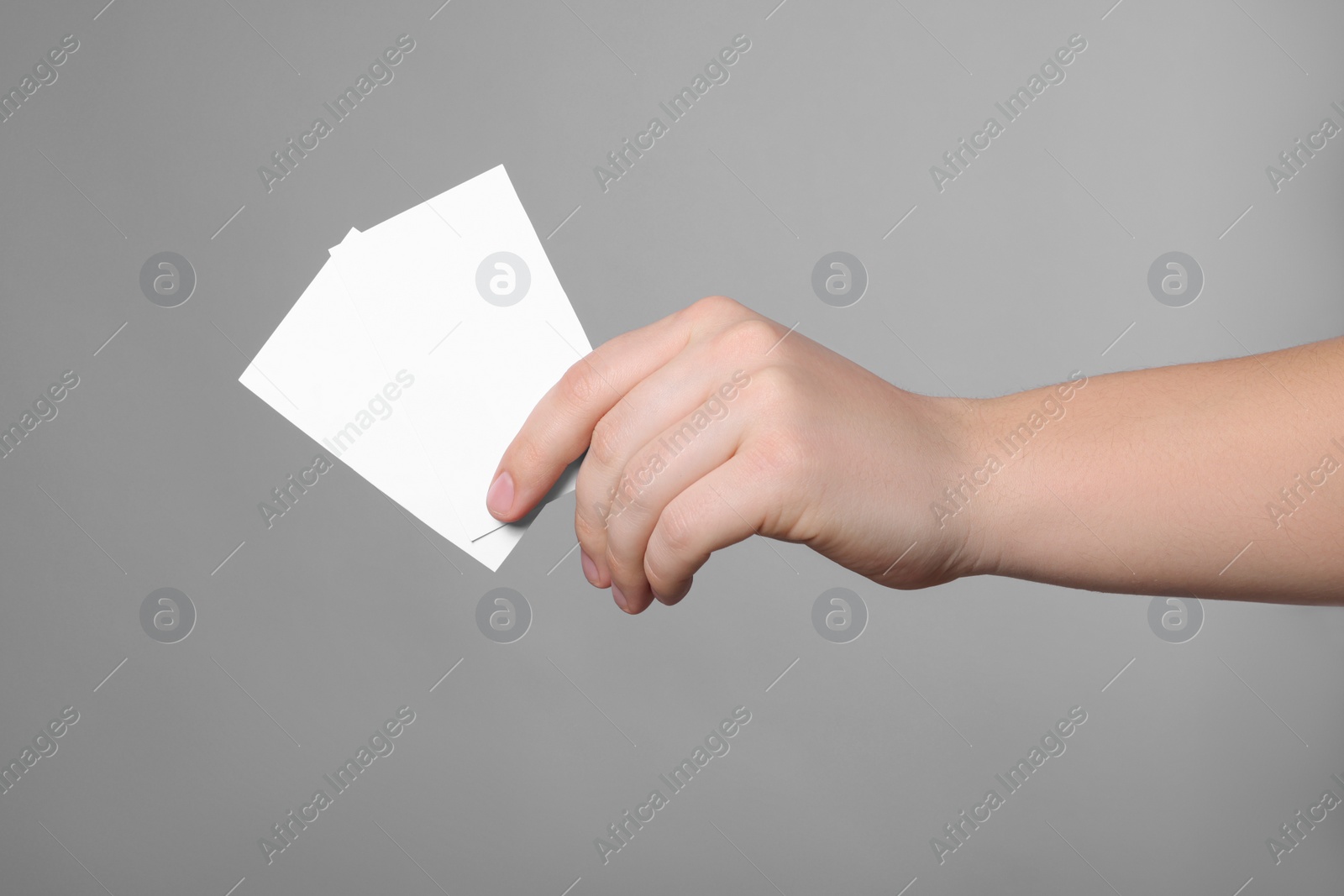 Photo of Woman holding paper cards on grey background, closeup. Mockup for design