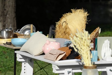 Photo of Small tables with many different items on garage sale outdoors